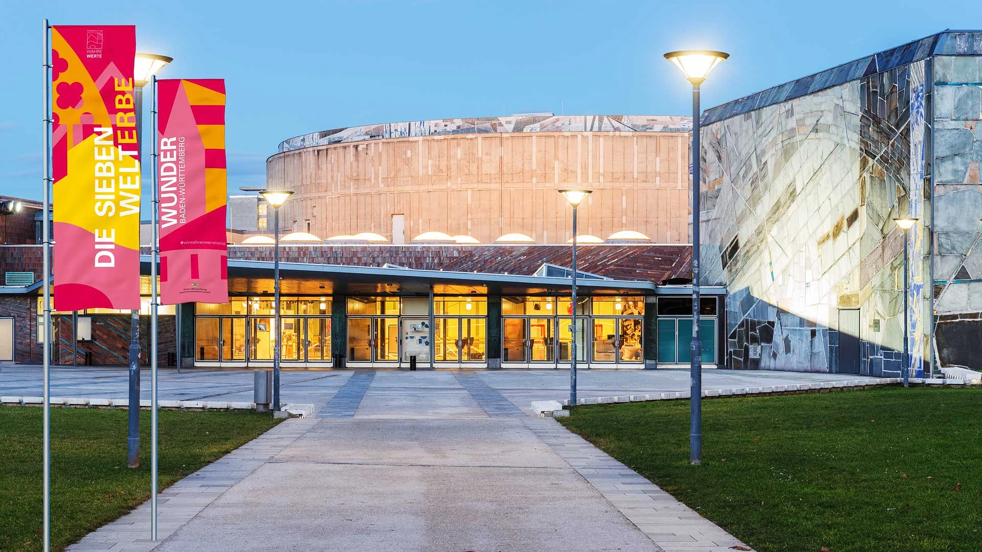 beachflags mit dem welterbe-schriftzug vor einem modernen museumsbau
